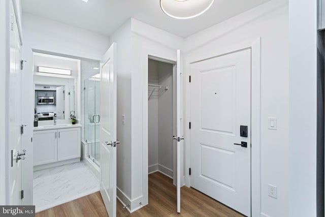 701 N Henry St Unit 212, Alexandria, VA 22314 - corridor featuring baseboards, a sink, and light wood-type flooring