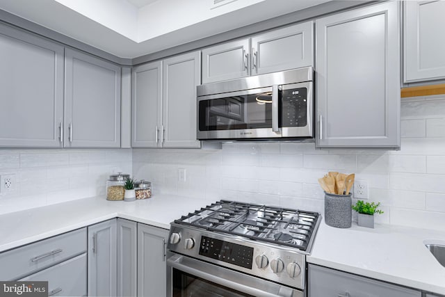 701 N Henry St Unit 212, Alexandria, VA 22314 - kitchen with stainless steel appliances, gray cabinetry, backsplash, and light countertops