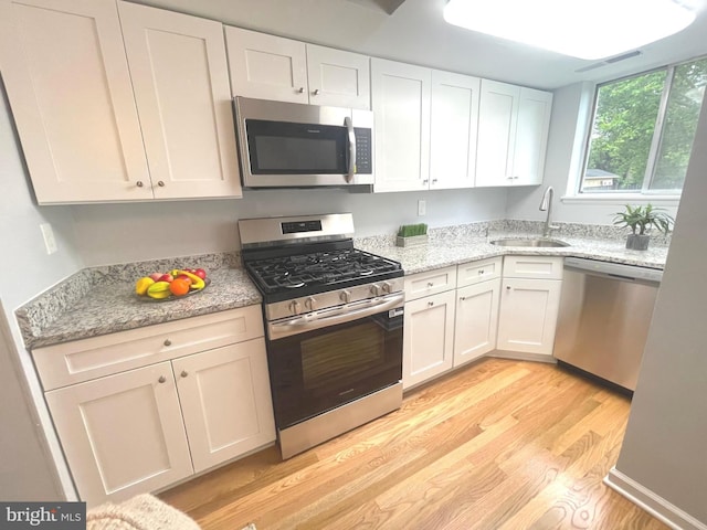 3700 N Rosser St Unit 104, Alexandria, VA 22311 - kitchen featuring stainless steel appliances, light wood-style floors, white cabinets, and light stone countertops