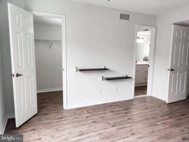 1504 Lincoln Way Unit 305, Mclean, VA 22102 - unfurnished bedroom featuring a walk in closet, wood finished floors, a closet, and baseboards