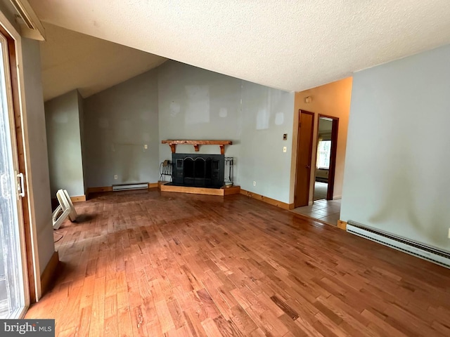 28 Myrtle Dr, Gerrardstown, WV 25420 - unfurnished living room featuring wood finished floors, lofted ceiling, a fireplace with raised hearth, baseboard heating, and a textured ceiling