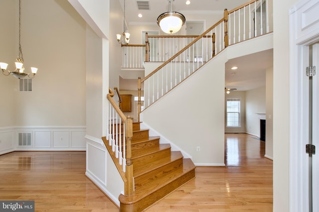 9573 5th Pl, Lorton, VA 22079 - stairway featuring a chandelier, wood finished floors, crown molding, a high ceiling, and a fireplace