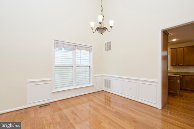 9573 5th Pl, Lorton, VA 22079 - unfurnished dining area with a chandelier, light wood-type flooring, a wainscoted wall, and a decorative wall