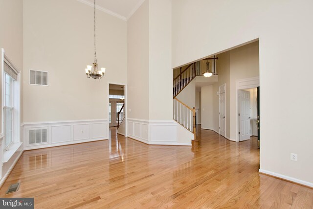 9573 5th Pl, Lorton, VA 22079 - empty room featuring stairway, a chandelier, crown molding, a high ceiling, and light wood-type flooring