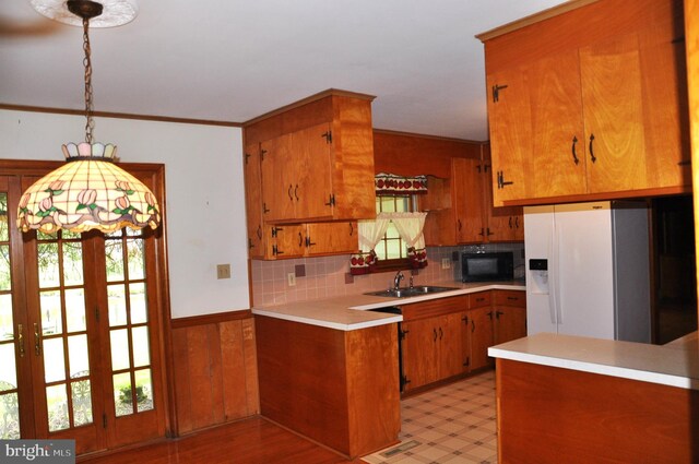3202 Holly Ln, Cambridge, MD 21613 - kitchen with black microwave, white fridge with ice dispenser, a sink, brown cabinetry, and light countertops