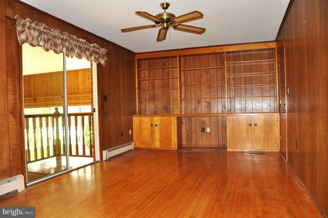 3202 Holly Ln, Cambridge, MD 21613 - empty room with a baseboard radiator, wooden walls, ceiling fan, and wood finished floors