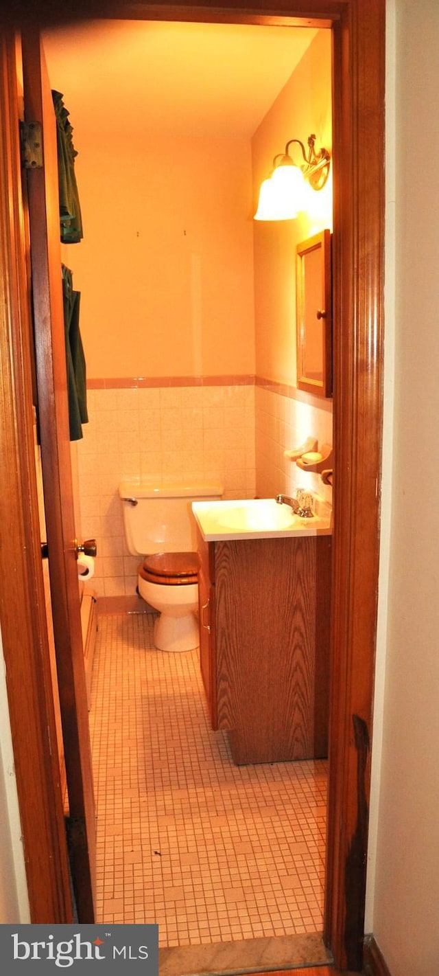 3202 Holly Ln, Cambridge, MD 21613 - half bathroom with vanity, toilet, wainscoting, tile patterned flooring, and tile walls