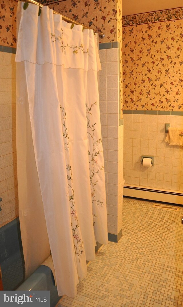 3202 Holly Ln, Cambridge, MD 21613 - full bathroom featuring tile walls, wallpapered walls, a wainscoted wall, baseboard heating, and shower / tub combo with curtain