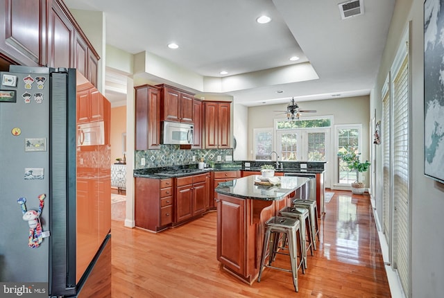 5968 Manorview Way, Alexandria, VA 22315 - kitchen with stainless steel appliances, a peninsula, a kitchen bar, light wood-style floors, and ceiling fan