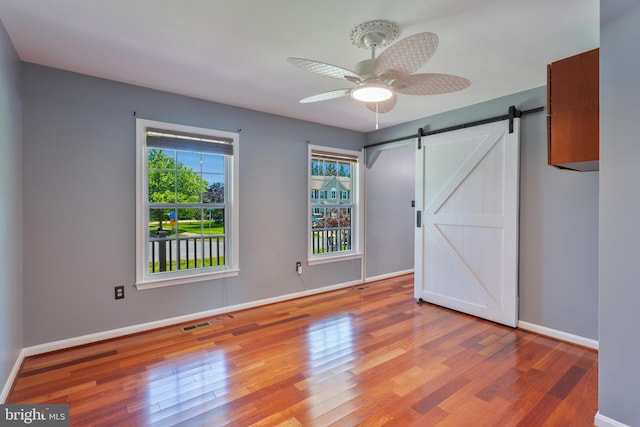 4109 Leisure Dr, Temple Hills, MD 20748 - unfurnished bedroom featuring wood finished floors, a barn door, baseboards, and a ceiling fan