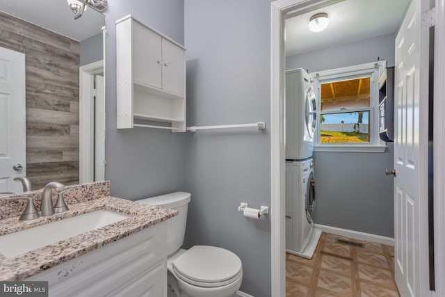 4109 Leisure Dr, Temple Hills, MD 20748 - bathroom featuring estacked washer and dryer, vanity, toilet, and baseboards