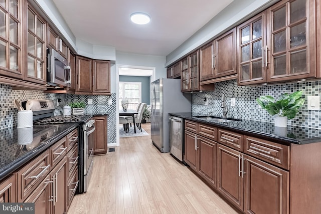 10447 Carriagepark Ct, Fairfax, VA 22032 - kitchen with appliances with stainless steel finishes, light wood-style floors, backsplash, dark stone counters, and glass insert cabinets