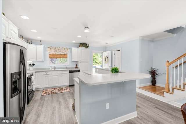 9729 Village Ln Unit 9715C, Ocean City, MD 21842 - kitchen with appliances with stainless steel finishes, ornamental molding, light wood-style flooring, white cabinetry, and a center island