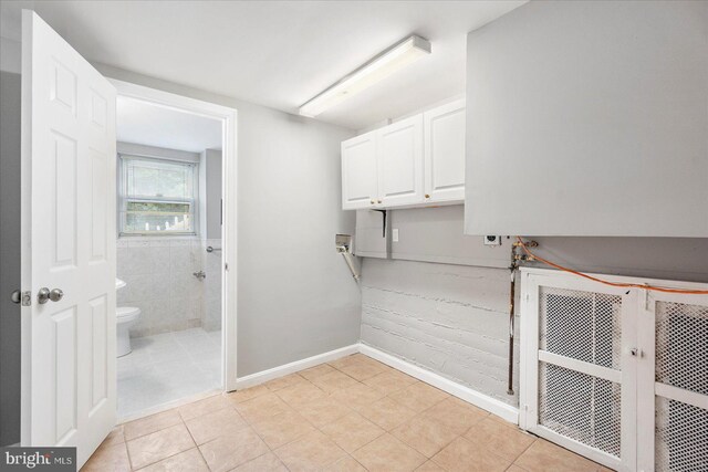 3910 The Alameda, Baltimore, MD 21218 - laundry area featuring hookup for a washing machine, cabinet space, light tile patterned floors, and baseboards