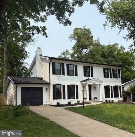 427 W St NW, Vienna, VA 22180 - colonial house featuring an attached garage, a chimney, driveway, and a front lawn
