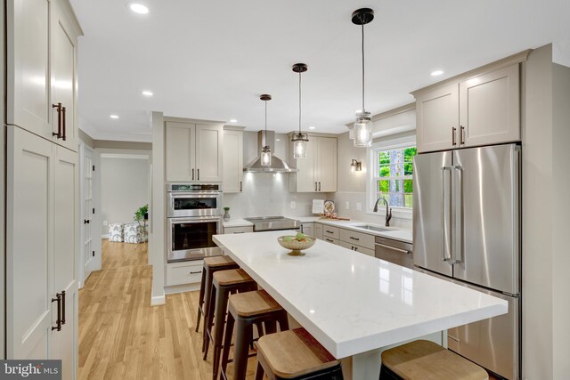 427 W St NW, Vienna, VA 22180 - kitchen featuring stainless steel appliances, a sink, wall chimney range hood, light countertops, and a kitchen bar