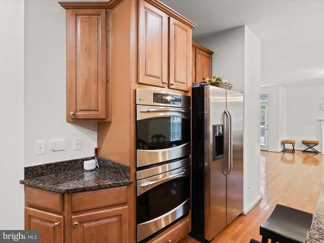 3903 Beeker Mill Pl, Chantilly, VA 20151 - kitchen featuring stainless steel appliances, light wood-style flooring, brown cabinets, and dark stone counters