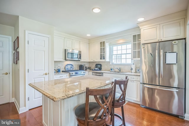 1 Hedge Row Rd, Princeton, NJ 08540 - kitchen with appliances with stainless steel finishes, glass insert cabinets, light stone counters, wood finished floors, and tasteful backsplash