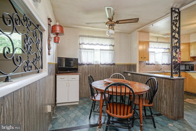 1103 Laurel Rd, Edgewater Park, NJ 08010 - dining room featuring a wainscoted wall, plenty of natural light, a ceiling fan, wood walls, and dark floors