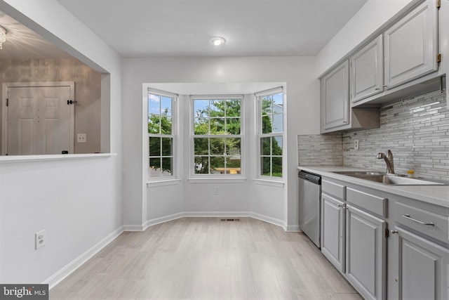 12307 Sandy Point Ct, Silver Spring, MD 20904 - kitchen with gray cabinetry, stainless steel dishwasher, light wood-style flooring, tasteful backsplash, and light countertops