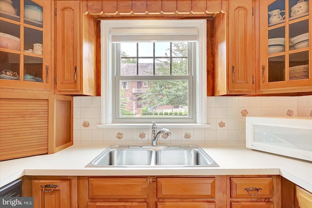 29 S Rockburn St, York, PA 17402 - kitchen featuring white microwave, a sink, backsplash, light countertops, and glass insert cabinets