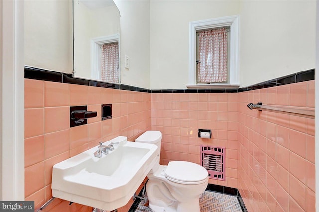 29 S Rockburn St, York, PA 17402 - bathroom featuring heating unit, tile walls, toilet, a wainscoted wall, and a sink