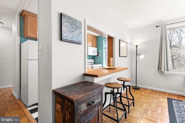 4100 W St NW Unit 314, Washington, DC 20007 - kitchen with white appliances, baseboards, butcher block counters, and a breakfast bar area