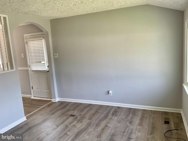 647 Elm St, Aberdeen, MD 21001 - spare room with wood finished floors, arched walkways, vaulted ceiling, and a textured ceiling