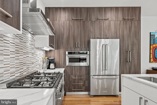 1401 S Carolina Ave SE Unit 1, Washington, DC 20003 - kitchen with appliances with stainless steel finishes, modern cabinets, wall chimney range hood, and light stone countertops