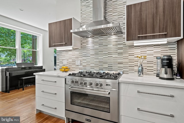 1401 S Carolina Ave SE Unit 1, Washington, DC 20003 - kitchen with stainless steel range with gas cooktop, wall chimney exhaust hood, backsplash, and modern cabinets