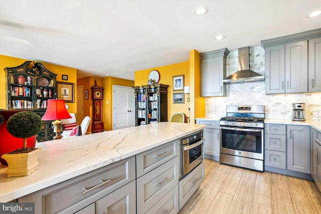 3001 Veazey Ter NW Unit 1632, Washington, DC 20008 - kitchen featuring stainless steel gas range, wall chimney range hood, gray cabinets, tasteful backsplash, and recessed lighting