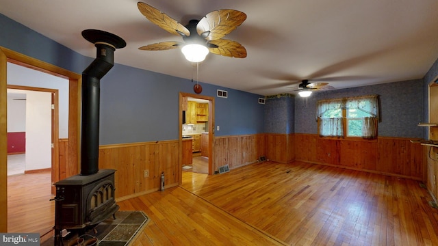6085 Mud Mill Rd, Camden Wyoming, DE 19934 - spare room with a wood stove, wainscoting, a ceiling fan, hardwood / wood-style floors, and wooden walls