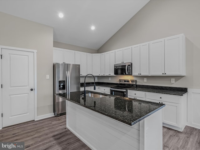 39 Mdg, Berkeley Springs, WV 25411 - kitchen featuring appliances with stainless steel finishes, an island with sink, wood finished floors, dark stone counters, and white cabinets