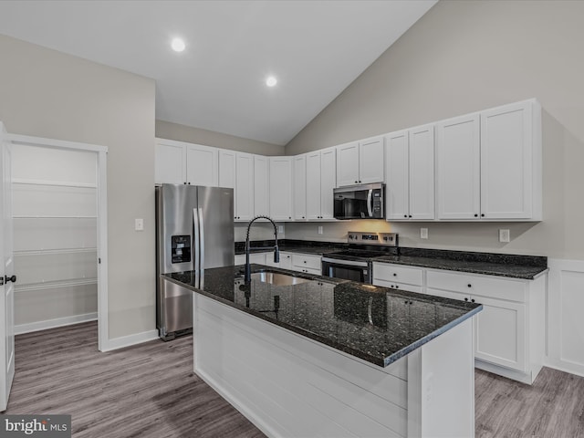 39 Mdg, Berkeley Springs, WV 25411 - kitchen featuring stainless steel appliances, a sink, light wood finished floors, dark stone countertops, and an island with sink