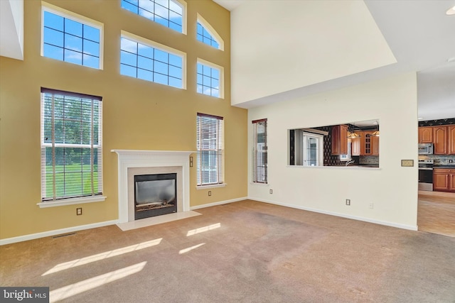 1215 Oakwood Ln, York, PA 17403 - unfurnished living room with light colored carpet, healthy amount of natural light, a fireplace with flush hearth, and a towering ceiling