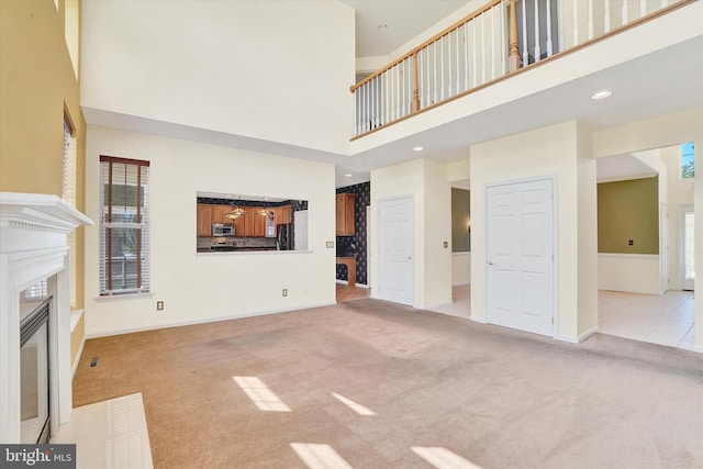 1215 Oakwood Ln, York, PA 17403 - unfurnished living room featuring carpet flooring, a high ceiling, a fireplace with flush hearth, baseboards, and recessed lighting