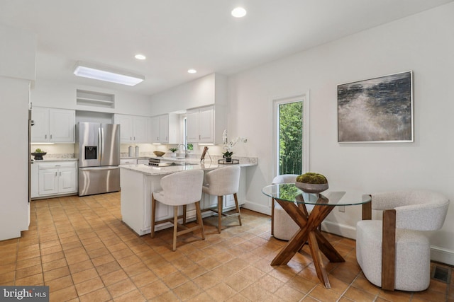 3233 Ellicott St NW, Washington, DC 20008 - kitchen featuring stainless steel refrigerator with ice dispenser, a peninsula, a breakfast bar area, white cabinets, and recessed lighting