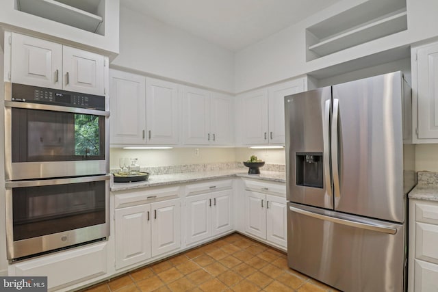 3233 Ellicott St NW, Washington, DC 20008 - kitchen featuring appliances with stainless steel finishes, light tile patterned flooring, white cabinets, and light stone countertops
