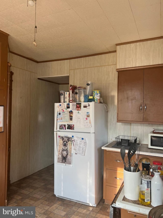 24 S 7th St, Shamokin, PA 17872 - kitchen featuring freestanding refrigerator, stainless steel microwave, wood walls, brick patterned floors, and crown molding