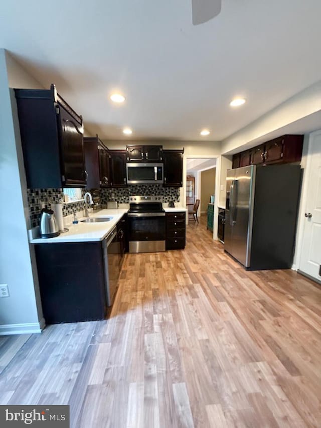 39410 Thomas Dr, Mechanicsville, MD 20659 - kitchen with appliances with stainless steel finishes, a sink, light countertops, decorative backsplash, and light wood-type flooring