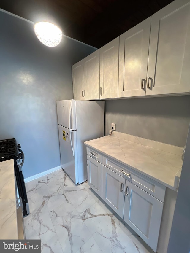 4379 Americana Dr Unit 201, Annandale, VA 22003 - kitchen featuring freestanding refrigerator, gas stove, light marble finish floors, baseboards, and white cabinetry