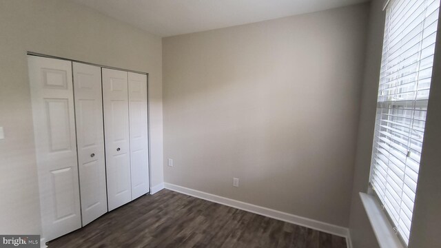 602 Moonglow Rd Unit 202, Odenton, MD 21113 - unfurnished bedroom featuring a closet, dark wood-style flooring, and baseboards