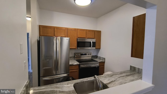 602 Moonglow Rd Unit 202, Odenton, MD 21113 - kitchen featuring stainless steel appliances, a sink, brown cabinets, and light stone countertops