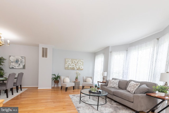 20976 Kittanning Ln, Ashburn, VA 20147 - living room featuring light wood finished floors, a chandelier, and baseboards
