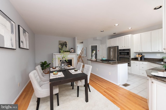 20976 Kittanning Ln, Ashburn, VA 20147 - dining area featuring a fireplace, light wood-style floors, baseboards, and recessed lighting