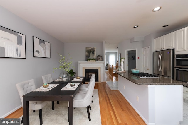20976 Kittanning Ln, Ashburn, VA 20147 - dining room with light wood finished floors, a fireplace, baseboards, and recessed lighting