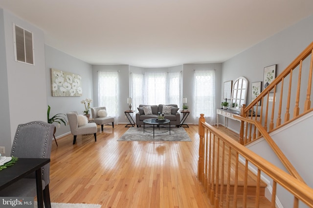 20976 Kittanning Ln, Ashburn, VA 20147 - living room featuring healthy amount of natural light, light wood-type flooring, stairway, and baseboards