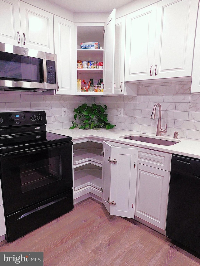 2241 Cartwright Pl, Reston, VA 20191 - kitchen featuring black appliances, a sink, white cabinets, light countertops, and light wood finished floors