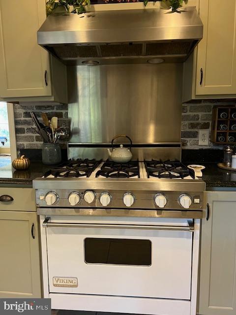 232 N Shore Ct, Seaford, DE 19973 - kitchen featuring gas stove, wall chimney range hood, dark countertops, backsplash, and white cabinets