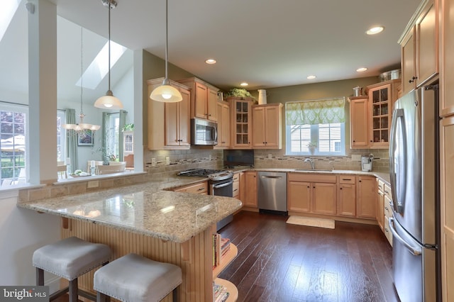 126 Windermere Dr, Palmyra, PA 17078 - kitchen with stainless steel appliances, a peninsula, a sink, dark wood-style flooring, and a breakfast bar
